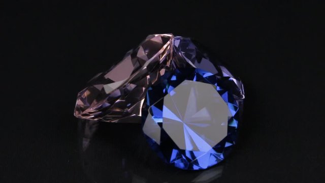 Rotation of three diamonds on a black background with a beautiful reflection.