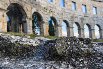 Fototapeta na wymiar Limestone (carbonate sedimentary rock) close-up with the interior of Pula Arena (Arena di Pola) on the background, Pula, Croatia - Image
