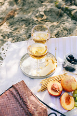 Two glasses of the white wine and tasty food and accessories  Summer picnic in the beach