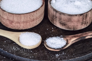 salt and sugar on the table in wooden spoons and cups.  the main ingredients for cooking: salt and sugar.
