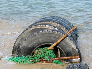 view of the sandy beach by the Baltic Sea. Seashore with old car tires and concrete, human waste,...