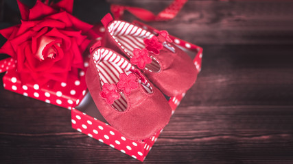 elegant red shoes for a newborn girl. children's beautiful shoes. girl's little red sandals in a box and a red rose.