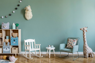 Scandinavian interior design of playroom with wooden cabinet, armchairs, a lot of plush and wooden toys. Stylish and cute childroom decor. Eucalyptus background walls. Copy space.  Template.