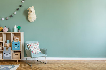 Stylish scandinavian newborn baby room with wooden cabinet, toys, children's armchair and pillow....