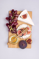 Wooden Board with Brie Cheese Figs Grapes and Honey Snack For Wine Autumn Harvest Food Vertical Top View