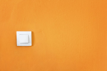 simple white switch on a bright orange wall