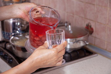 homemade cold sugared strawberry juice in the kitchen filling up the glass