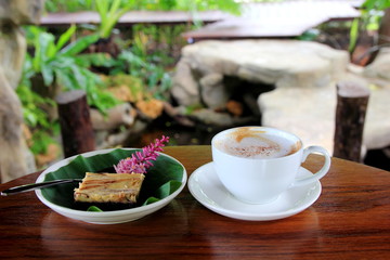 Coffee in white cup and Chocolate Brownie on brown wooden.in the garden.