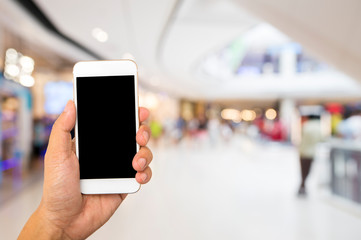 Hand hold black smartphone on blur shopping mall background