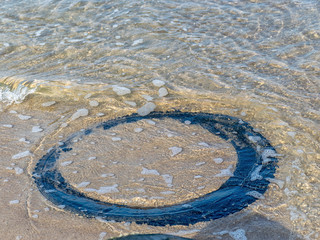 view of the sandy beach by the Baltic Sea. Seashore with old car tires and concrete, human waste,...
