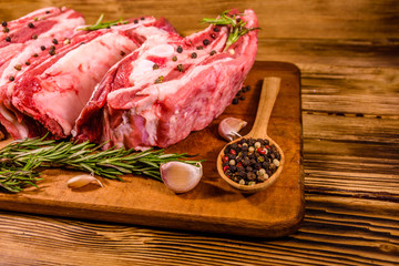 Raw pork ribs with spices, garlic and rosemary on a cutting board