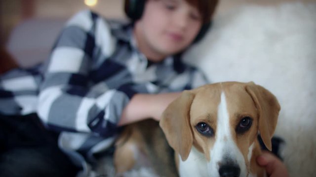 4k Child Listening to Music in Headphones and Petting Dog