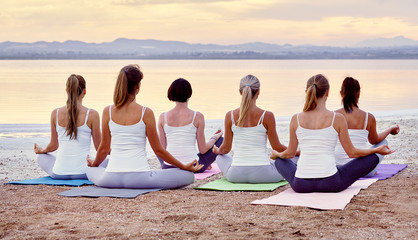Back view women sitting in lotus pose meditating outdoors panoramic image