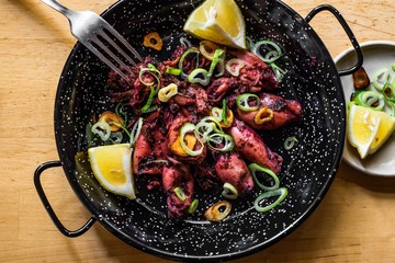 Calamari on grill on black pan.