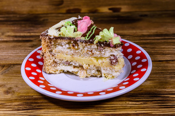 Plate with slice of Kiev cake with cream, nuts and meringue on a wooden table