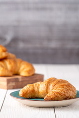 Flacky crispy fresh croissant rolls with blue background