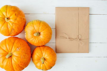Top view of orange Pumpkins with gift in brown paper package tied up with strings on old wooden background. Thanksgiving and Halloween concept. Copy space for text and design