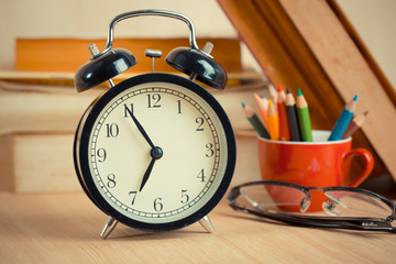 Alarm clock on reading table with color pencil background