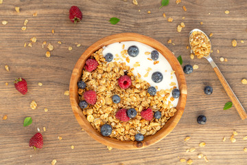 Yogurt with granola and berries fresh raspberries and blueberries on wooden background. Top view. Delicious and healthy Breakfast smoothie. Vegetarian food.