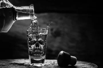  Drink bottle and glass with alcohol content. Image of translucent skull in glass. Alcoholism, addiction or poison concept. © RHJ