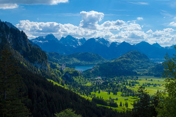 Fototapeta na wymiar Bergflanke mit frischem Grün im Vordergrund, blauer See und Bergmassiv im Hintergrund