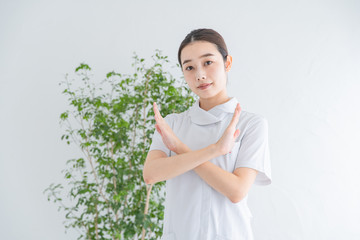 「バツ」のサインをする白衣の女性