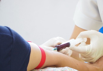 Closeup of blood draw process of a man in the hospital for health check up to diagnose the level of blood sugar or glucose and cholesterol in his annual health checkup program. Healthcare and medical 