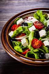 Greek salad in bowl on wooden table