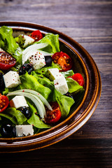Greek salad in bowl on wooden table
