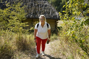 Modern girl in glasses on a background of an old wooden house. Girl on a camping trip.