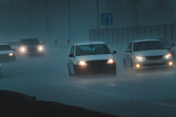 Cars go at night in the rain on the road.