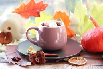 Cup of coffee, rose,  apple, pumpkins, leaves, spices on a wooden surface on a window background, home comfort concept, Thanksgiving, autumn season
