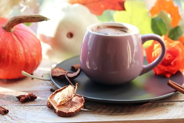 Cup of coffee, rose,  apple, pumpkins, leaves, spices on a wooden surface on a window background, home comfort concept, Thanksgiving, autumn season