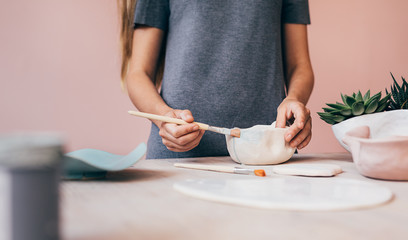 Obraz na płótnie Canvas Unrecognizable woman painting ceramic bowl in her studio