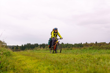 Fototapeta na wymiar cyclist traveler rides through an autumn meadow on a cloudy day