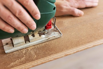 Installation laminate or parquet in the room, worker cuts a laminate of a certain length with a jigsaw
