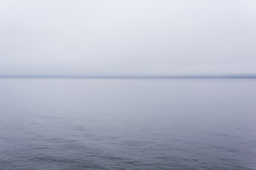 cold body of water with a distant shore hidden by fog