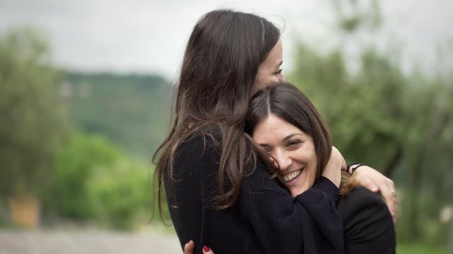 Two young happy fresh and beautiful friends together. Two attractive girls holding happily each other and hugging smiling in the park. Friendship between two young pretty women.