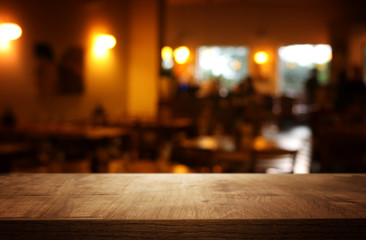 Fototapeta na wymiar background of wooden table in front of abstract blurred restaurant lights