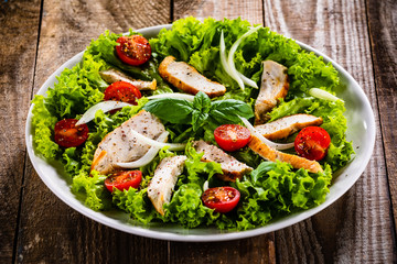 Caesar salad on white plate on wooden table
