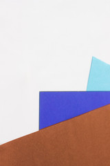 Three colored papers with blue, violet and brown colors on white in the form of a triangle. Background, abstraction