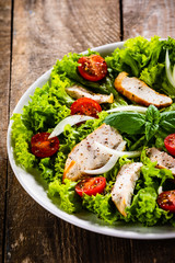 Caesar salad on white plate on wooden table