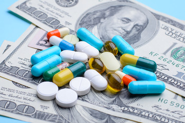 Many different pills capsules on money background. Symbol of high price on medicine
