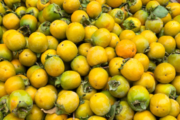 Yellow immature persimmon background. Persimmon on the counter of the market in Athens.