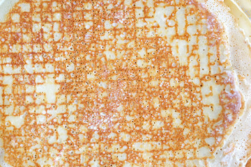 A thin pancake background. Cooking thin pancakes with holes in the pan. Fried buttered pancake view from above, delicious homemade dessert for tea.