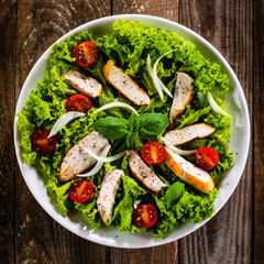 Caesar salad on white plate on wooden table