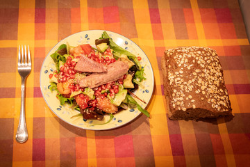 mesa con mantel y tenedor y un plato de ensalada con bonito y pan