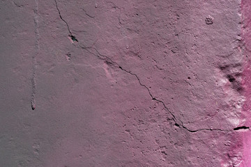 texture of a painted wall. cement plate purple color background. wall with bumps, a crack and small pits.