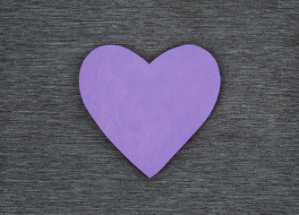 Wooden heart shape, on gray material, as a background texture with design space.