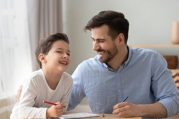 Happy dad and little kid son laughing drawing together